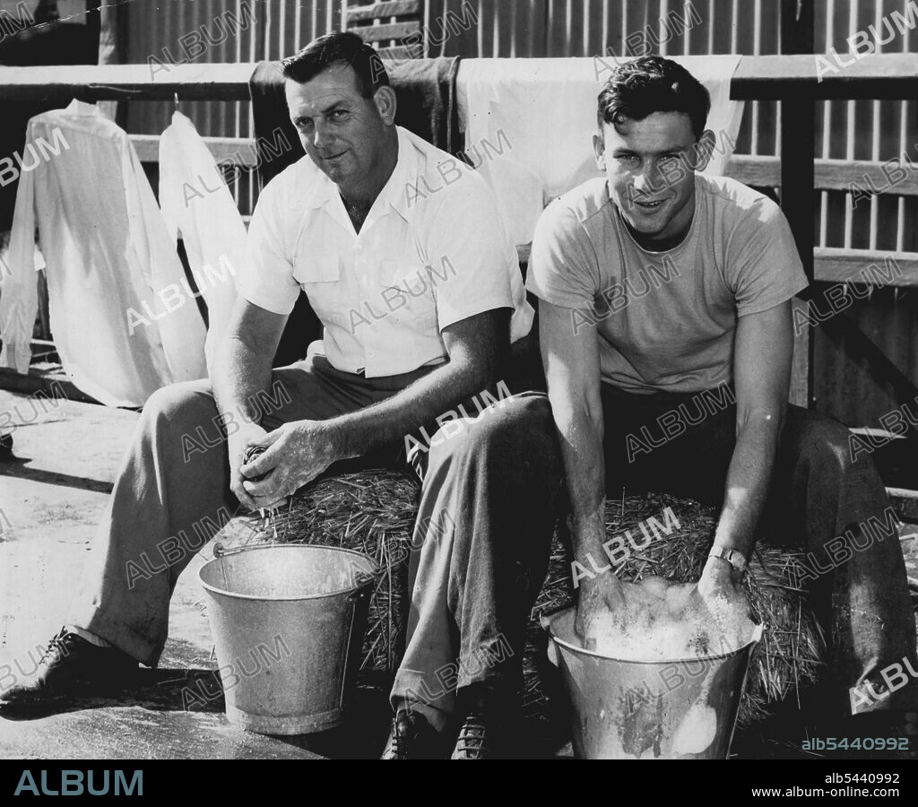 Bruce Abernethy (left) of Nowra ***** Darrell Martin of Griffith doing their week-end washing in front of a cattle pavilion at the Showground to-day. Both men look after cows from Austral Park. April 10, 1955. (Photo by Ted Foster).
