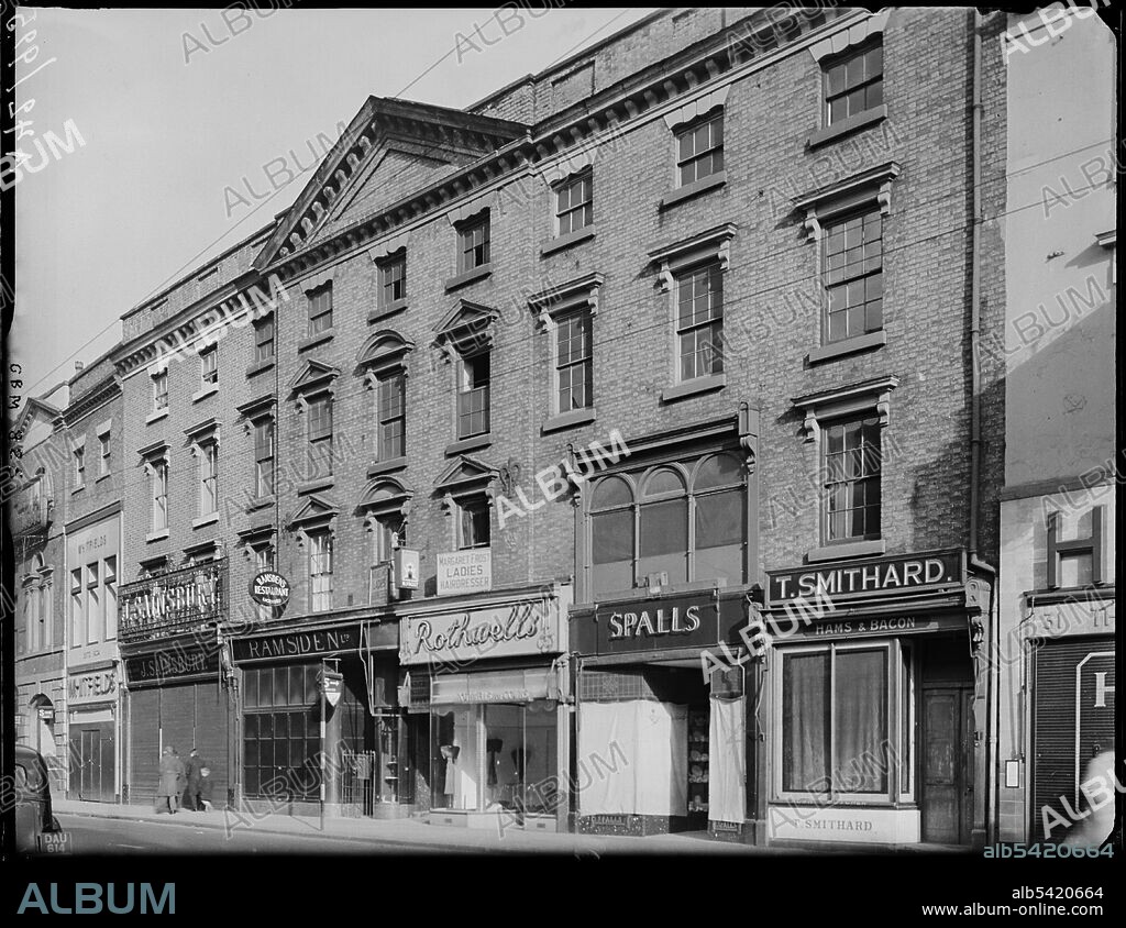 GEORGE BERNARD MASON. Devonshire House, 36 Corn Market, Derby, 1942. The exterior of Devonshire House at 32-36 Corn Market. Devonshire House was built in the mid 18th century as the Derby town house of the Dukes of Devonshire - a place to reside when in Derby for pleasure or civic business. During the 19th and 20th centuries this once grand house saw a gradual decline in social status, prompted in circa 1814, when the 6th Duke opted to stay in alternative accommodation when in town. Devonshire House was converted for commercial use, with shops moving into the ground floor rooms and a market hall being built on the garden. Today only the northern 4 bays (those further from the camera) survive. The remainder was demolished in 1969, to be replaced by a Littlewood's Store (now Primark).