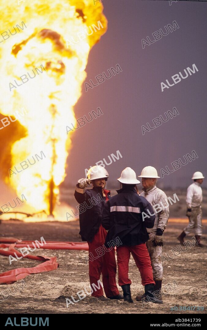 Kuwait City, Kuwait; March 1991. American oil rig workers contracted by the Kuwaiti government attempt to plug and stop oil wells burning out of control in the Al-Ahmadi oil fields located on the outskirts of Kuwait City. The oil fields were set on fire by retreating Iraqi troops hoping to create some cover from American airplanes strafing their positions. The fires and smoke caused one of the greatest environmental disasters of modern times. Nearly 800 oil wells were set ablaze by the retreating Iraqi army and the fires were not fully extinguished until November 6, 1991, eight months after the end of the war. The fires consumed an estimated six million barrels of oil daily. Their immediate consequence was a dramatic decrease in air quality, causing respiratory problems for many Kuwaitis. The sabotage of the oil wells also impacted the desert environment, which has a limited natural cleansing ability. Un-ignited oil from the wells formed about 300 oil lakes that contaminated around 40 million tons of sand and earth.