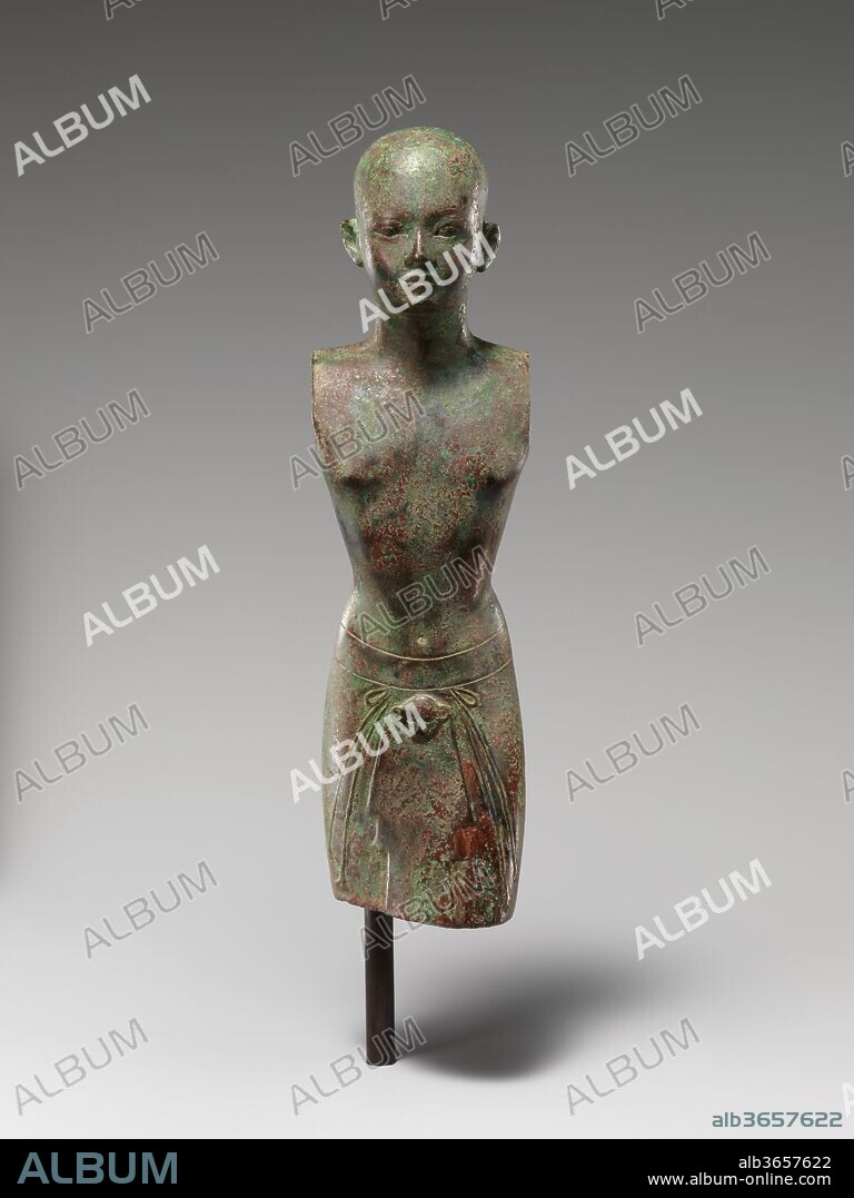 Kushite priest wearing garment with leopard's head and tassels, subsequently adapted for a king. Dimensions: H. 21 x D. 5.5 cm (8 1/4 x 2 3/16 in). Dynasty: Dynasty 25. Date: ca. 712-664 B.C..
The rounded head with small features atop a slender but powerful body identifies this statue as Kushite. Beneath the bare torso, the lower body is clothed with a kilt. From a wide belt hangs a leopard's head, signifiying priestly office, and long cords ending in vegetal tassels. The arms and legs, now missing, would have been attached separately.