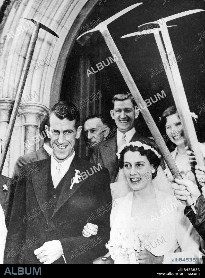 Orig. bildtext... EVEREST CLIMBER WEDS IN NEW ZEALAND. The marriage between Sir edmund Hillary - who with Sherpa Tensing made the successful ascent of Mt. Everest - and Miss Louise Rose, took place at the Diocean School Chapel, Auckland, New Zealand. Photo shows: Sir Edmund Hillary with his bride leaving under an archway of ice-picks. In rear is Mr. George Lowe who was also a member of the Everest Expedition. Orig. bildtext... ÄNNU EN ERÖVRING. En av Mount Everests uppmärksammade besegrare, Sir Edmund Hillary, har i dagarna gift sig med Miss Louise Rose i Auckland, Nya Zealand och här ses det lyckliga paret lämna kyrkan under en äreport av is-hackor. Mannen i bakgrunden är George Lowe, ven han medlem av Mount Everest-expeditionen. Anm. E Hillary, 1919-2008, nyzeeländsk bergsbestigare och forskningsresande. Deltog i den brittiska expeditionen till Mount Everest 1952-53 och blev en av de första som nådde bergets topp 29 maj 1953 CD109 Bergsklättrare Ishackor persons: EDMUND HILLARY;GEORGE LOWE;LOUISE ROSE sites: AUCKLAND;NYA ZEELAND.