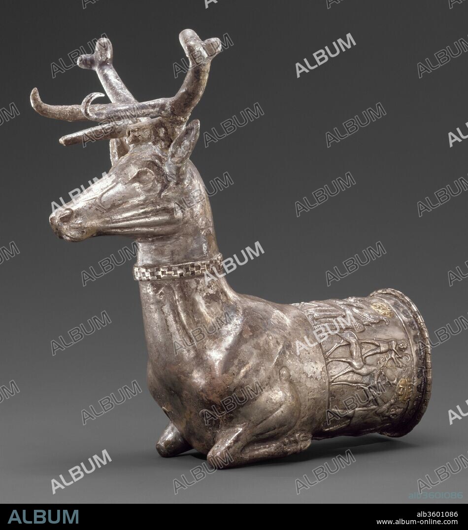 Vessel terminating in the forepart of a stag. Culture: Hittite. Dimensions: H. 18 cm. Date: ca. 14th-13th century B.C..
By 1700 B.C., people speaking Hittite--an Indo-European language--had founded a capital at Bogazköy (ancient Hattusha) and, under a series of powerful kings, established a state in central Anatolia. The Hittite army attacked and partly destroyed Babylon in 1595 B.C., and in 1285 B.C. fought a battle against the Egyptian king Ramesses II at Qadesh in Syria.
This silver rhyton--a drinking vessel in the form of an animal with a pouring hole in its chest--in the form of a stag was hammered from one piece that was joined to the head by a checkerboard-patterned ring. Both the horns and the handle were attached separately. A frieze depicting a religious ceremony decorates the rim of the cup, suggesting the uses for which the cup was intended. A prominent figure, thought to be a goddess, sits on a cross-legged stool, holding a bird of prey in her left hand and a small cup in her right. She wears a conical crown and has large ears, typical of Hittite art. A mushroom-shaped incense burner separates her from a male god who stands on the back of a stag. He, too, holds a falcon in his left hand, while with his right he grasps a small curved staff. Three men are shown in profile, moving to the left and facing the deities. Each holds an offering to the divinities. Behind the men is a tree or plant against which rests the collapsed figure of a stag. Hanging from the tree is a quiver with arrows and an object that appears to be a bag. Two vertical spears complete the frieze and separate the stag from the goddess.
Cult scenes or religious processions are commonly represented in the art of the Hittite Empire, and texts make frequent reference to trees and plants associated with rituals or festivals. The texts also tell us that spears were venerated objects, so it is possible that the stag, killed in hunt, as is suggested by the quiver and bag, was being dedicated to the stag god. Hittite texts also mention that animal-shaped vessels made of gold, silver, stone, and wood, in the appropriate animal form, were given to the gods for their own use. Though the precise meaning of the frieze on this vessel remains a matter of conjecture, it is possible that it was intended to be the personal property of the stag god.
