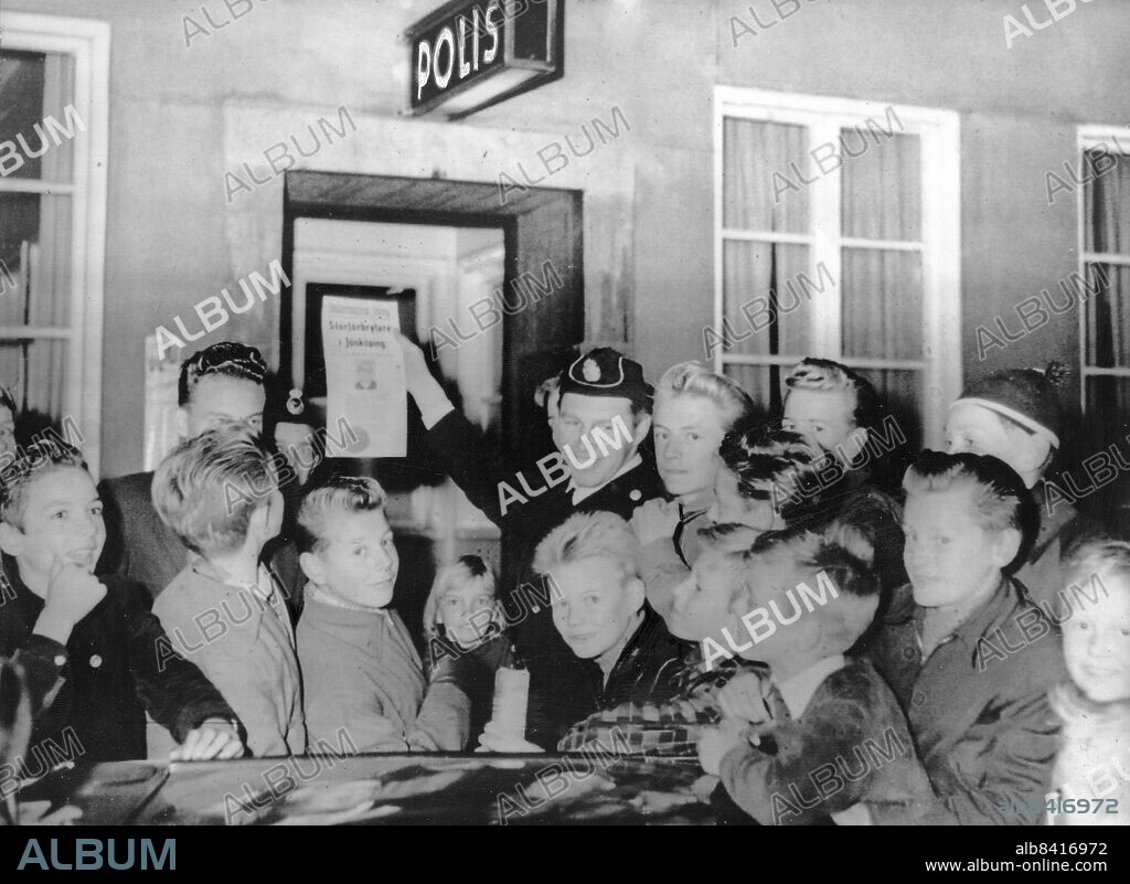 JÖNKÖPING 1956-09-17. Polisman Karl Erik Karlsson visar efterlysningen av dynamitarden och mästerrymmaren Sölving Holmström för ett gäng ungdomar.. Foto: Folke Hellberg / DN / TT / Kod: 23. ** SvD OUT**.