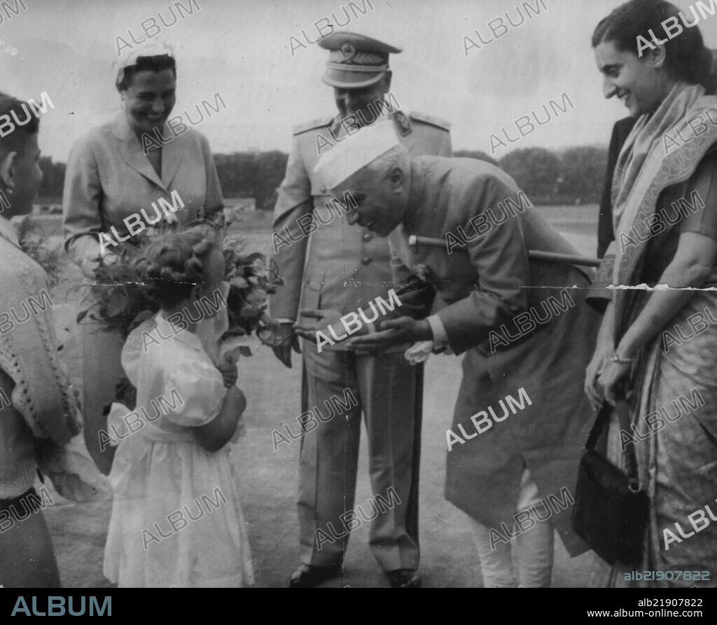 Bouquet For Nehru -- Prime Minister of India, Jawaharlal Nehru receives flowers from an unidentified girl on arrival at Bulgrade Airport, June 30. Looking on at centre is Marshal Tito of Jugoslavia, his wife at left. At right is Nehru's daughter, Mrs. Indira Gandhi. July 25, 1955. (Photo by Associated Press Photo).