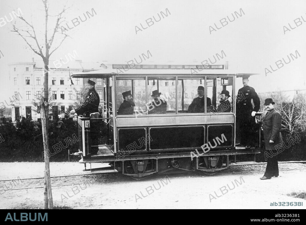 Orig. bildtext... 50 jahre Lichterfelde. DIE ELEKTRISCHE STRASSENBAHN DER WELT. Dieser Tage feiert der idyllische Villenvorort Lichterfelde bei Berlin sein 50 jähriges Bestehen als selbständige Gemeinde. Bei dieser Gelegenheit erinnert man sich der Tatsache, dass hier vor nunmehr 47 Jahren im Mai des Jahres 1881 die erste elektrische Strassenbahn der Welt ihren Betrieb eröffnete. Werner von Siemens baute diese unter Benutzung einer für den Bau der Kadettenanstalt angelegten Materialzuführungsbahn. Sie, nahm den Personalenverkehr zwischen der Hauptkadettenanstalt dem Bahnhof Lichterfelde an der Anhalter Bahn auf. Der erste elektrische Strassenbahnwagen in Lichterfelde 1881. Anm. Spårvagnar CD68 persons: WERNER VON SIEMENS* sites: LICHTERFELDE ;TYSKLAND PhotoDate:1881-??-??.