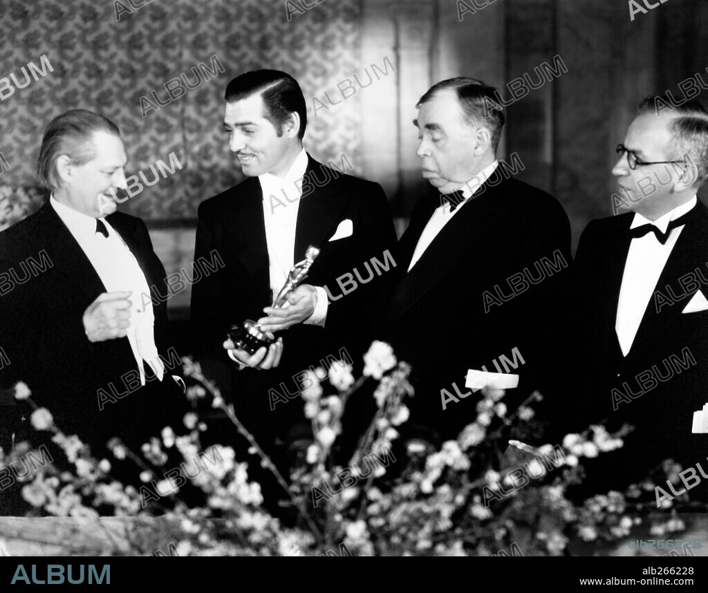 CLARK GABLE y LIONEL BARRYMORE. 7ª Edición de los Premios Oscar / 1935. 
Clark Gable premiado como mejor actor por "Sucedió una noche". Le acompaña el actor Lionel Barrymore y dos miembros de la Academia. 1935