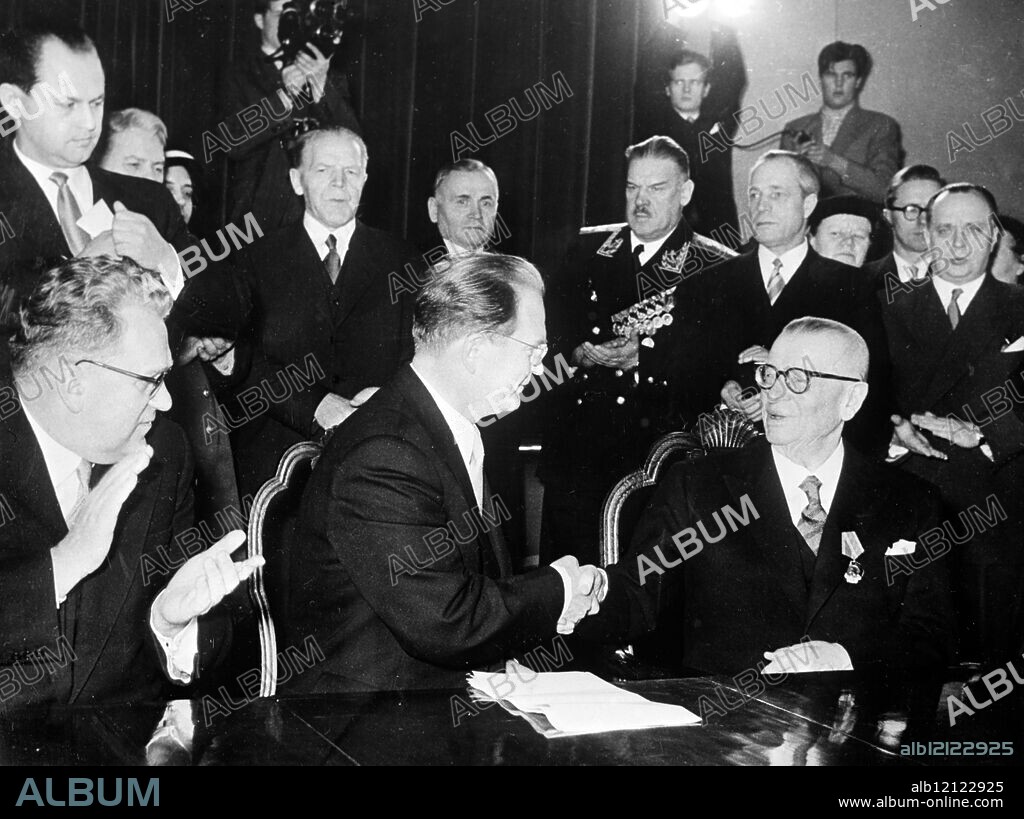 Helsinki: Finnish President Paasikivi (right) shakes hands with Soviet Vice Prime Minister Pervuchin after the document had been signed at the Soviet Embassy here returning the Porkkala naval base to Finland. Appluading at left is Soviet Ambassador Lebedev. The base was leased to the Russians in 1944. 28 January 1956.