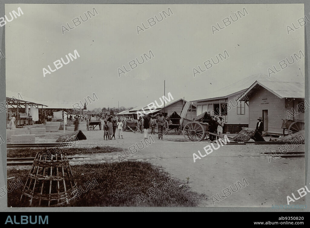 Bireuen station, The station at Bireuen, the beginning of the Gajo road. Along the road some villagers, near the railroad two Dutchmen. Framed photo in an album of 107 photos about the construction of the Gajo road on North Sumatra between Bireuen and Takinguen between 1903-1914., anonymous, Noord-Sumatra, 1903 - 1913, photographic support, height 138 mm × width 200 mm.