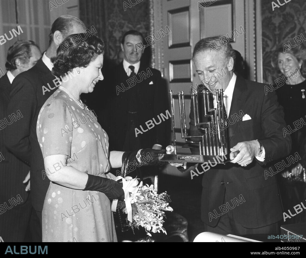 Greville Janner presents the Queen with a menorah at the Jewish Commonwealth Leaders Conference, December 1982. Greville Janner (born 1928) was President of the Board of Deputies of British Jews, the main representative body of British Jewry, from 1978 to 1984. He has been involved in efforts to seek compensation and restitution for Holocaust victims, and helped arrange the 1997 London Nazi Looted Gold conference. He was Chair of the Parliamentary Select Committee on Employment from 1994-1996.