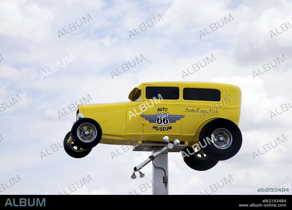 Yellow vintage car sits atop a large pole advertising the Auto Museum in Santa Rosa, New Mexico.