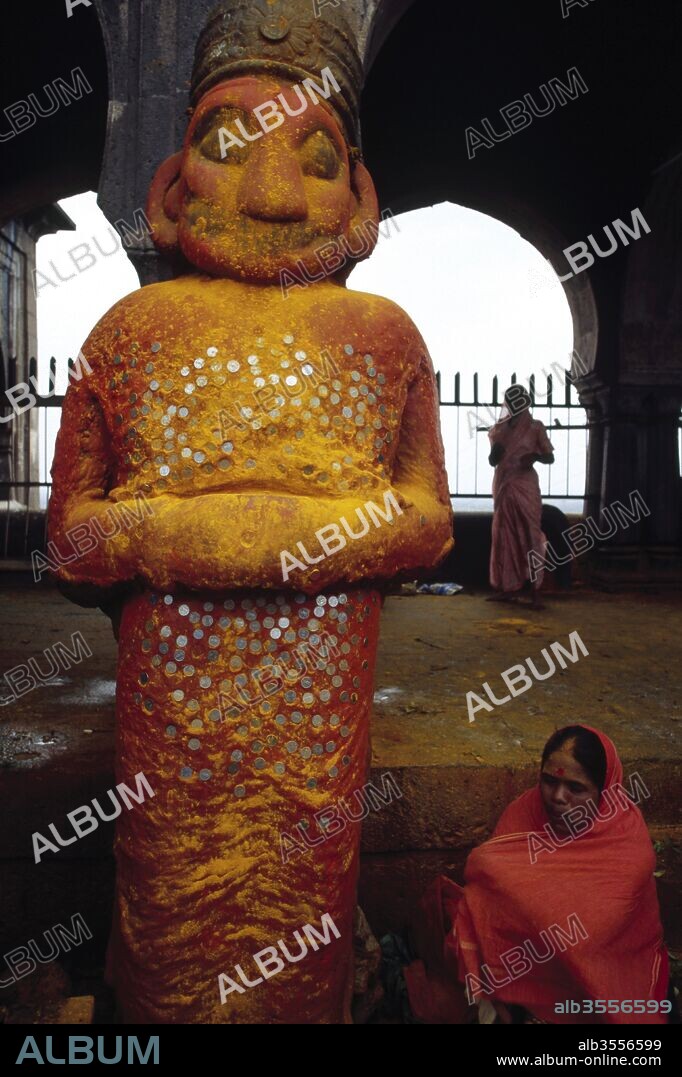 Tall orange red statue of demon Malla who had converted from a demon to a devotee of Khandoba, Somvati Amas, Jejuri, Maharashtra, India.
