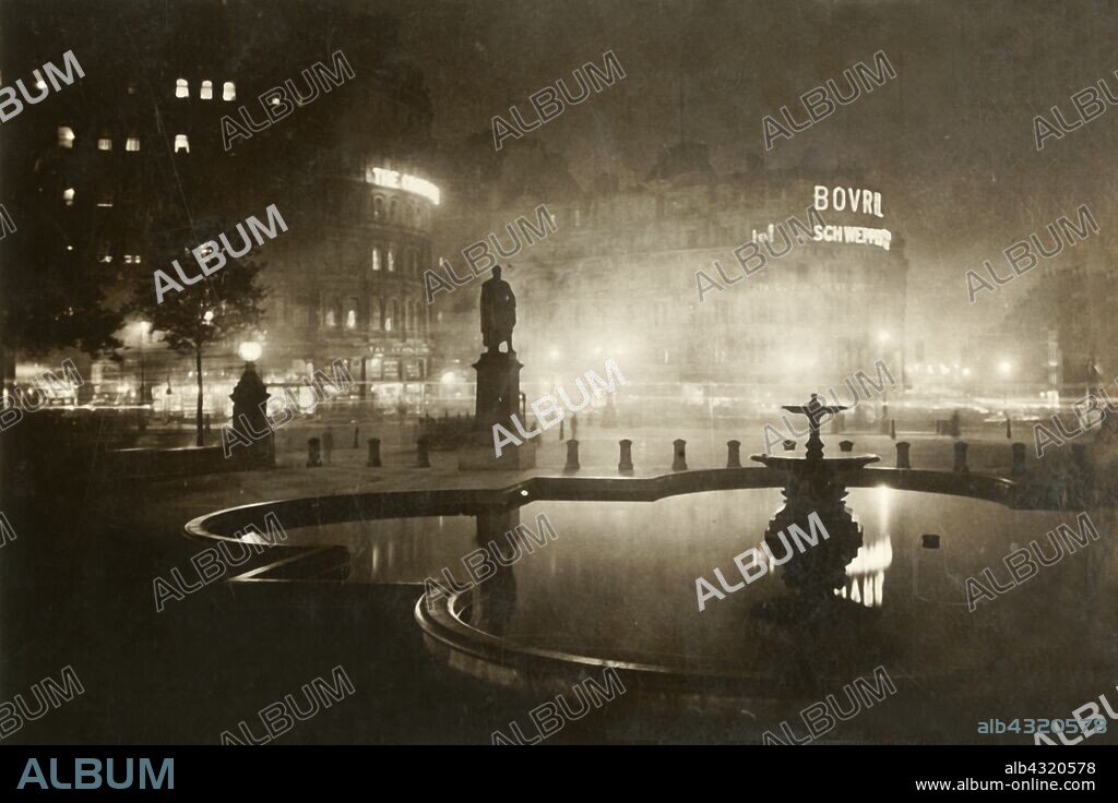 'Trafalgar Square. Looking Towards Charing Cross. London by Night', 1928. Neon advertising for Bovril and Schweppes, reflected in the water of the Trafalgar Square fountains. Beyond is a statue of Major General Sir Henry Havelock by William Behnes. Postcard.