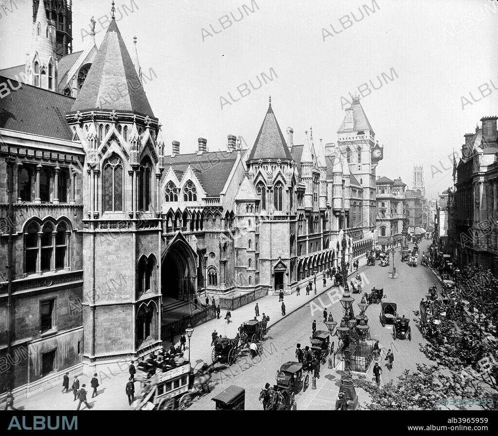 Royal Courts of Justice, Strand, London, 1882-1916. Carriages are waiting for hire, while horse buses are also visible. The photograph is looking east down the Strand towards St Dunstan in the West. The courts were completed to George Edmund Street's Gothic Revival designs in 1882.