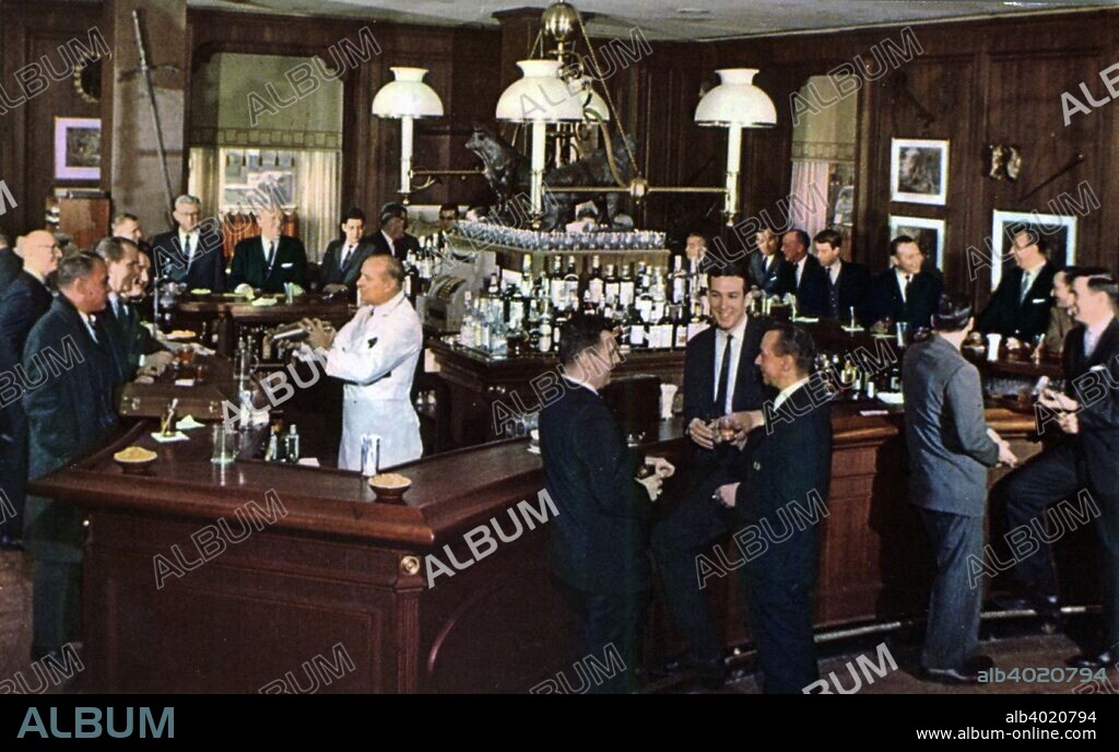 Bull and Bear Restaurant and Pub, New York City, New York, USA, 1965. Vintage postcard showing the interior of the Bull and Bear Restaurant and Pub. Men in business suits stand around the bar talking to each other.