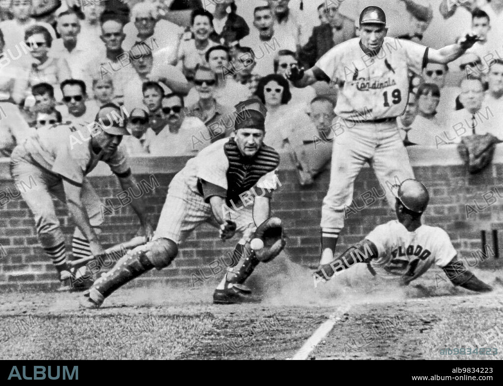 St. Louis, MIssouri July 10, 1965 Curt Flood of the St. Louis Cardinals scores as he slides into home in the ninth inning of a game with the Chicago Cubs. Catcher Ed Bailey awaits the ball while Bob Skinner, who also scored, looks on.