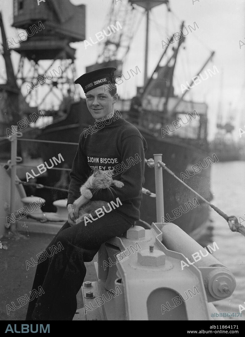 ANTARTIC RELIEF SHIP SAILS. When the ex-Boom Defence Vessel the John Biscoe , left Southampton she carried a relief party of men for the Falkland Islands Dependencies Survey . The ship is taking stores and mail for the Empire's loneliest scientists men who , for periods ranging from 18 to 30 months have been carrying out surveys work and scientific research in the Antarctic . When the John Biscoe makes her return trip she will bring some of the men home to Britain . PICTURE SHOWS:- Ginger , the ships cat with Roddey Bonner, from the Falklands pose for a picture before sailing from Southampton. October 13 1948.