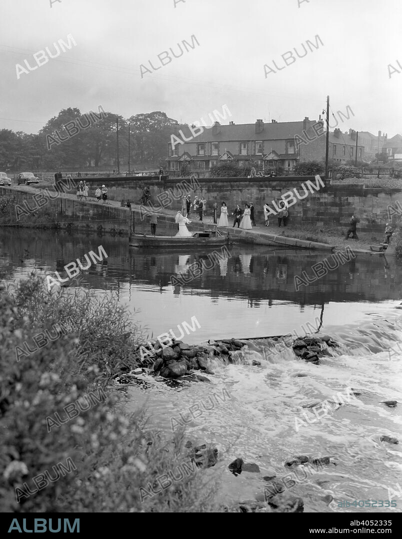 Ferry boat wedding party, Mexborough, South Yorkshire, 1960. A wedding party crosses the River Don on a trditional rope pulled barge.