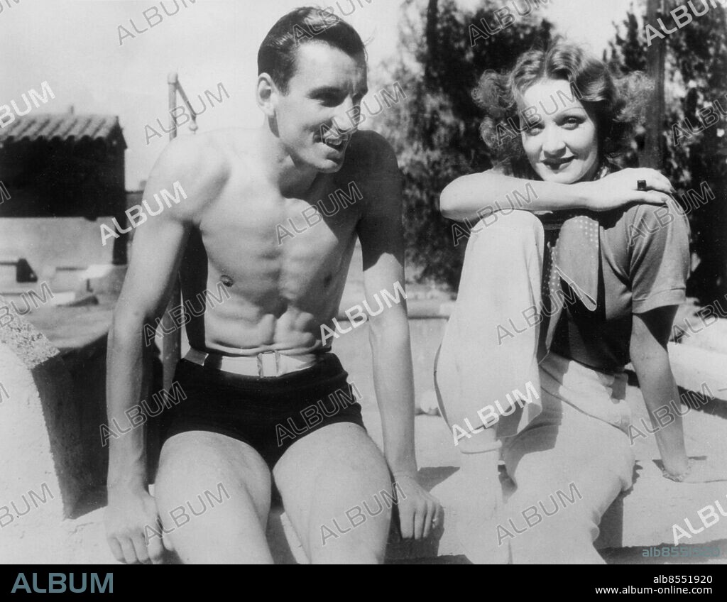 Orig. bildtext... On the little winter oasis known as Palm Springs, in the Desert near Hollywood, Fred Perry, world tennis champion, meets Marlene Dietrich, the famous film star. They attended the opening of the Desert Inn, always a big social occasion at this time of the year. Anm. Dietrich, Marlene, 1901-92, tysk-amerikansk skådespelerska och sångerska Perry, Fred, 1909-95, brittisk tennisspelare Badbyxor Bar överkropp Leenden Filmskådespelare CD294 persons: FRED PERRY;MARLENE DIETRICH sites: TYSKLAND*;PALM SPRINGS;KALIFORNIEN;USA.