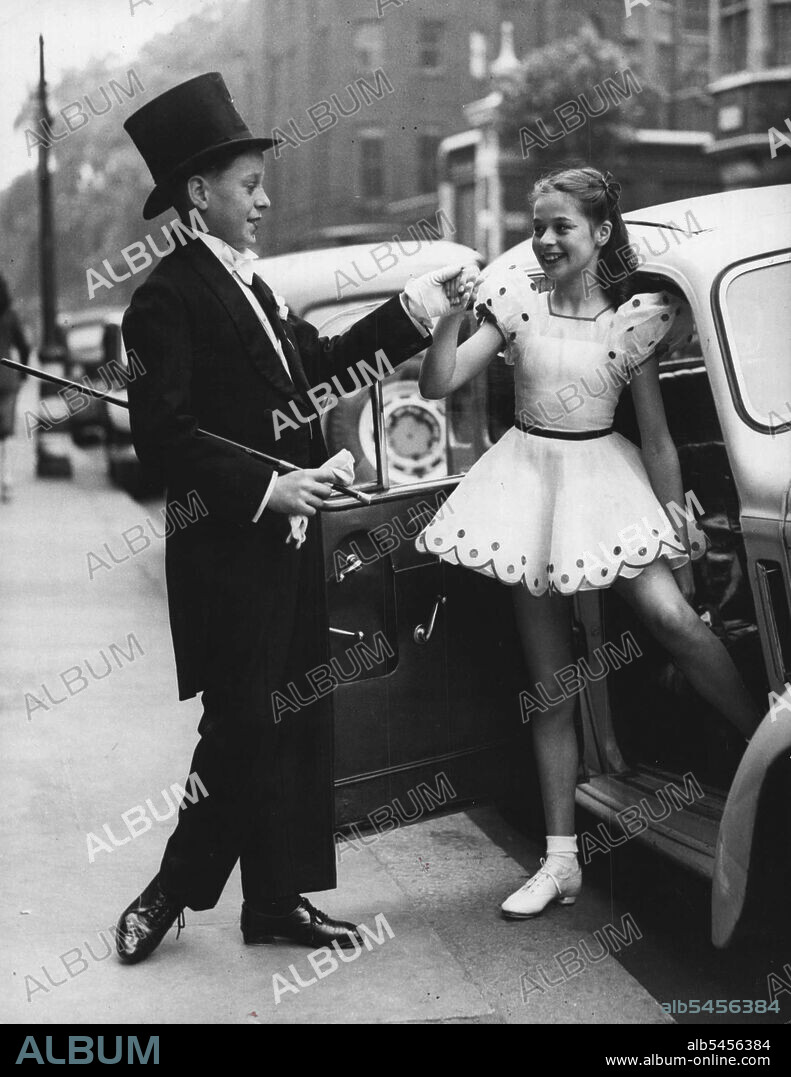 The Complete Gentleman - Master David Harding, aged 12, of Cornwall, completes the young gentleman role as he assists Miss Marion Astill, aged 11, of Slough, Bucks. They are both taking part in a preliminary heat in the Tap Dancing competition being held at King George Hall, W.C.l., this morning for the All-England dancing championships in aid of the Sunshine Homes for Blind Babies. June 20, 1947. (Photo by Reuterphoto).