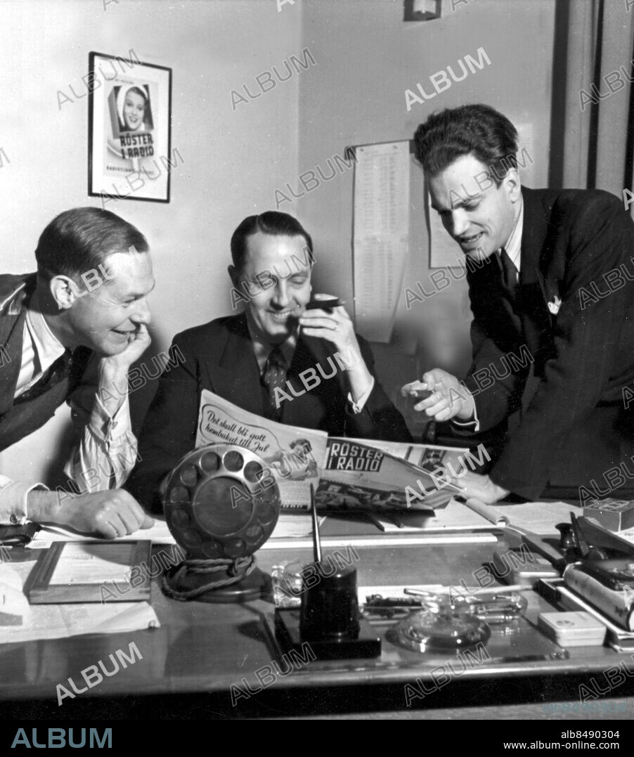 STOCKHOLM 1940.. Röster i radio-redaktionen.. Not. Radiotjänst Stockholm Redaktionen av Röster i radio Chefred. Wadsten red. Frithiof Lindgren tv.red. Manne Berggren t.h. Mikrofon:Plättlaggen som var den första typen av mik.som använd. av tv(...)radion Anm. Arbetsrum Skrivbord Cigarrer persons: Carl-Åke Wadsten ;Frithiof Lindgren ;Manne Berggren sites: STOCKHOLM ;SVERIGE.