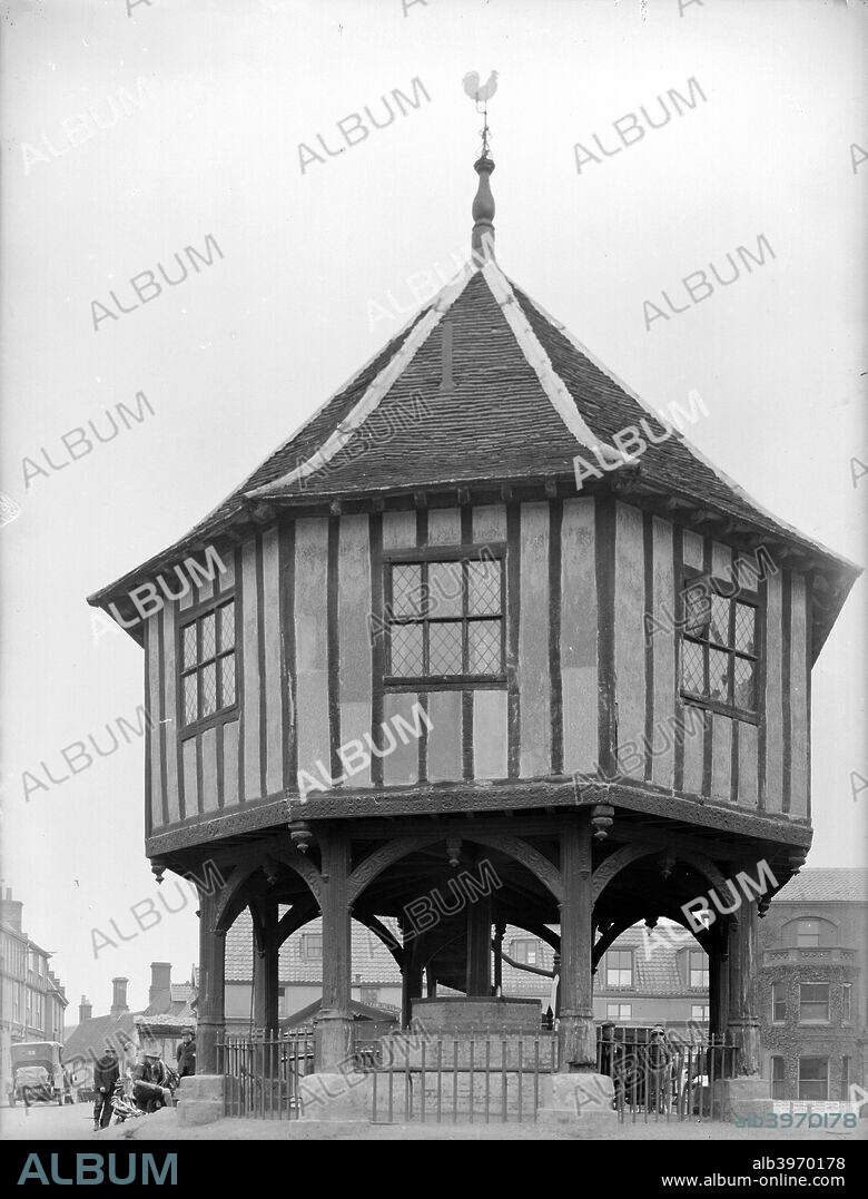 Market Cross, Wymondham, Norfolk, 1924. The Market Cross at Wymondham, built 1617-18 to replace the medieval structure lost in the fire of 1615. The upper floor of this octagonal structure is carried on decorated arched braces; the plaster infill is also decorated, a technique common to East Anglia. The space below is surrounded by railings.