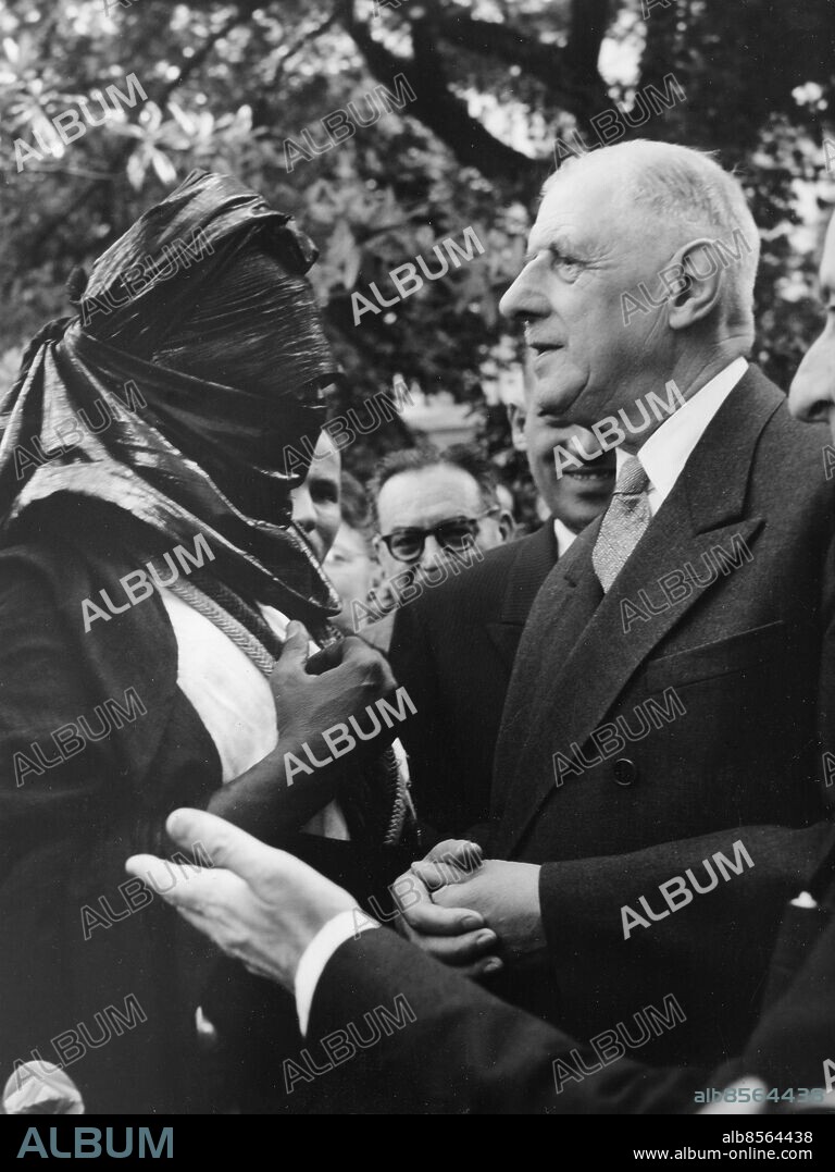 Orig. bildtext... LE GENERAL DE GAULLE, PRESIDENT DE LA REPUBLIQUE a rendu visite, au ministère du Sahara, a des personnalités d'Outre-Mer venues a Paris a l'occasion de la fète nationale du 14 juillet. - Voici Bey Ag Akhamouk, Amenokal du Hoggar présenté au Général de Gaulle. 13.7.61. Anm. Bey Ag Akhamouk, berberledare i Algeriet 1950-1975. C de Gaulle, 1890-1970, fransk statsman och militär, regeringschef 1944-1946 och 1958-1959, president 1959-1969. Ahaggar (Hoggar), bergsområde i Sahara, Algeriet Beslöjad Besökare Etnicitet Maskeringar Profiler Traditionell klädsel CD676 persons: CHARLES DE GAULLE;BEY AG AKHAMOUK sites: FRANKRIKE;ALGERIET*.