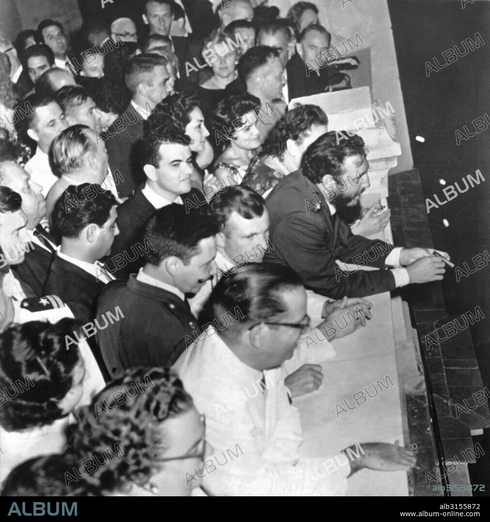 Havana, Cuba:  July 26, 1961 Cuban Premier Fidel Castro leans on the presidential palace balocony during a celebration for Russian cosmonaut Yuri Gagarin. Gagarin is standing directly behind Castro, and President Osvaldo Dortieos is in the foreground with glasses and white suit.