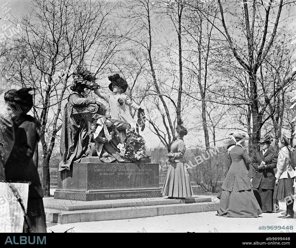 Full-length portrait of Mrs. F. L. Frank and Miss Anna Morgan laying wreaths on the William Shakespeare Statue, located at the foot of West Belden Avenue in Lincoln Park, in the Lincoln Park community area of Chicago, Illinois. The statue was created by William Ordway Partridge.