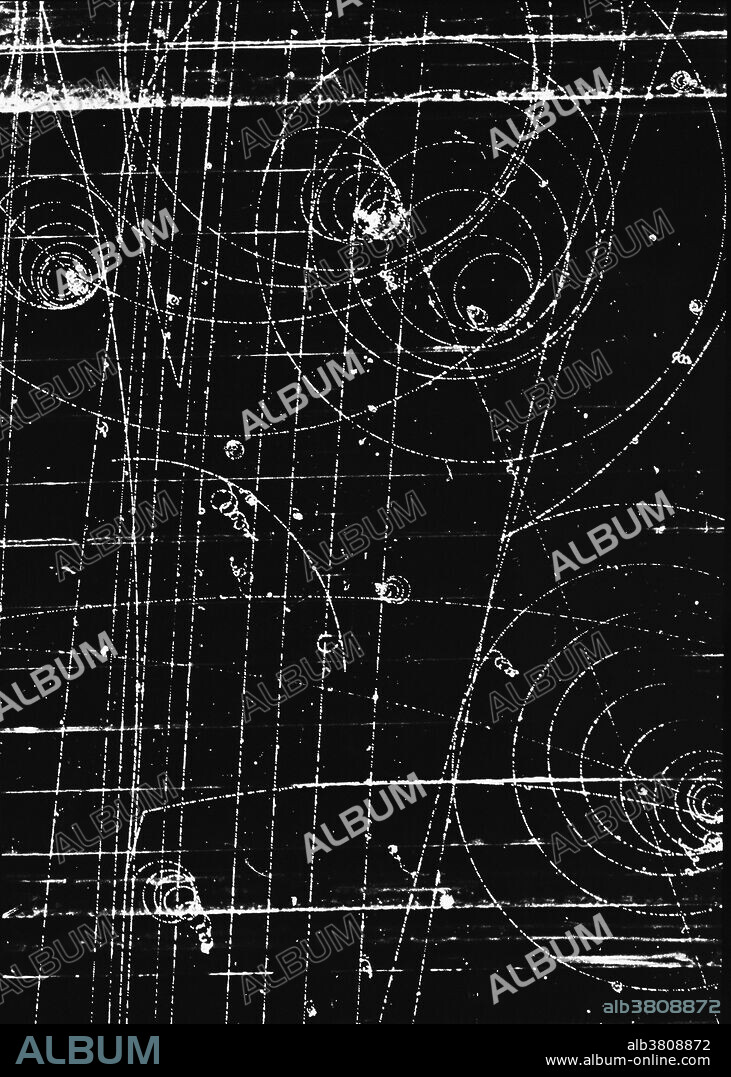 First observation of omega-minus particle. In this historic photograph from the 80-inch (200cm) bubble chamber at the Brookhaven National Laboratory, a negative kaon enters at bottom left & collides with a proton in the chamber's hydrogen to produce 3 particles, including the omega-minus, which consists of three strange quarks. The omega travels a short distance before decaying into a negative pion, which veers to the right across the bottom part of the picture, & a neutral xi particle which leaves no track. Discovery of the omega in 1964 confirmed Murray Gell-Mann & Yuval Ne'eman's classification of subatomic particles, the "Eightfold Way".