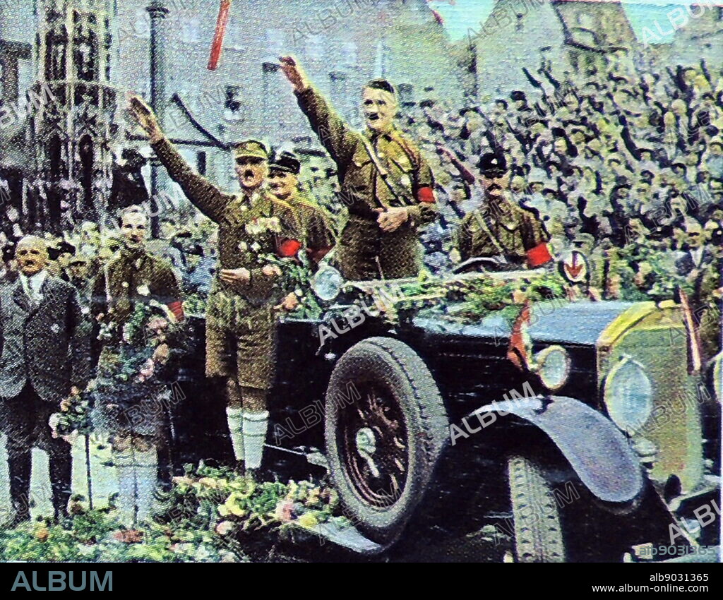 Hitler attending a Nazi Party rally in Nuremberg, standing to salute in his car. Julius Streicher in Grey suit stands to teh left of the picture while Rudolf Hess is seen immediately to Hitler's left behind the car. 1927.