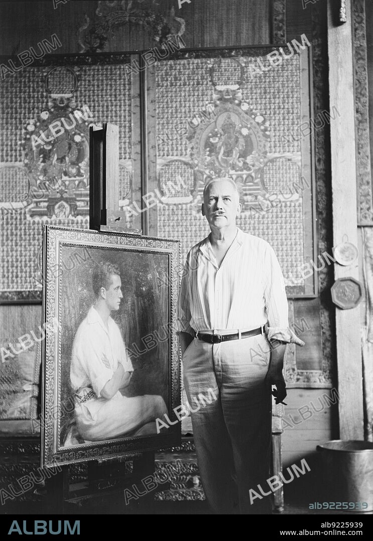 ARNOLD GENTHE. Albert Herter between 1932 and 1942. American artist, painter, interior designer, illustrator and muralist - in studio with painting, thangkas behind.