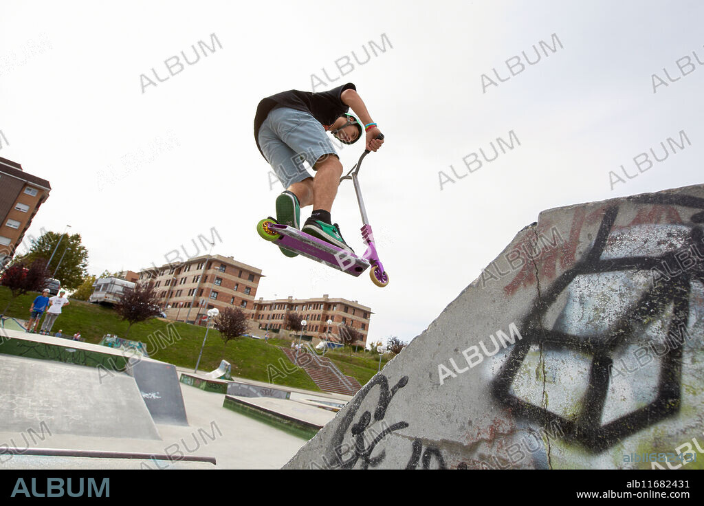 Teenager with city scooter in Skate park, Leioa, Bizkaia, Basque Country, Spain.