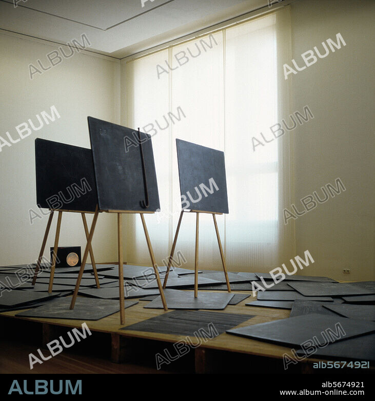 JOSEPH BEUYS. Beuys, Joseph, born 1921. - Richtkr{fte (Directional Force) 1974/77. Installation upon wooden platform. 100 black boards with chalk inscriptions. 3 wooden easels each holding one black board, and others. Installation size: 1186 × 521cm. Photograpg: Berlin Exhibition, 1988). Berlin, SMB, Nationalgalerie.