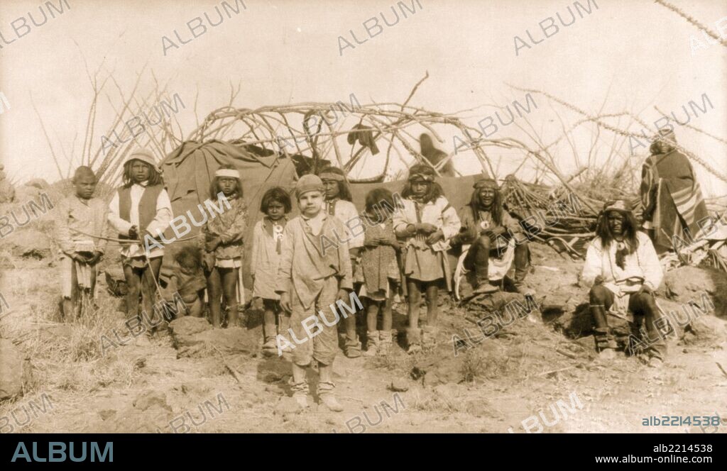 The captive white boy, Santiago McKinney in Geronimo's Camp, with group of Indians, mostly children, in front of partially constructed tent, before Geronimo's surrender to Gen. Crook, March 27, 1886.