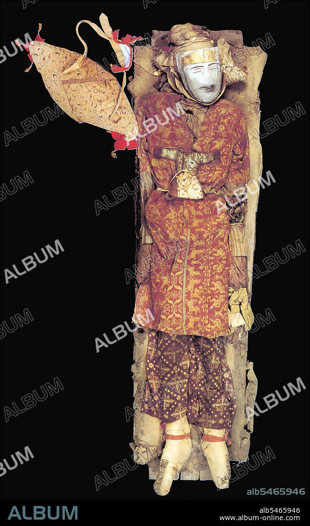 The best preserved of the corpses discovered at the cemetery at Zaghunluq in the Tarim Basin, is the 'Yingpan Man'. The two metres tall, 2,000 year old Caucasian mummy was discovered in 1995. His face was blond and bearded and was covered with a gold foil death mask; he also wore an elaborate golden embroidered red and maroon wool garments with images of fighting. His head rests on a pillow in the shape of a crowing cockerel. The Zaghunluq cemetery contained 29 mummies, dating from 1800-500 BC.