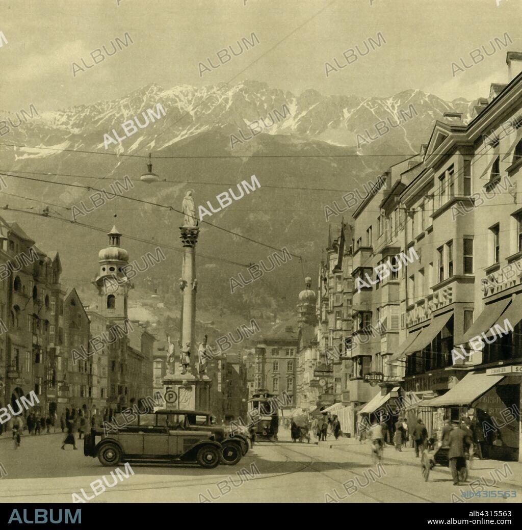 Maria-Theresien-Strasse, Innsbruck, Tyrol, Austria, c1935. Street named after Queen Maria Theresa, with a view of St Anne's Column and the Alps beyond. The monument comemmorates the expulsion of the last Bavarian troops from the Tyrol on St Anne's Day (26 July) 1703, during the War of the Spanish Succession. From "Österreich - Land Und Volk", (Austria, Land and People). [R. Lechner (Wilhelm Müller), Vienna, c1935].