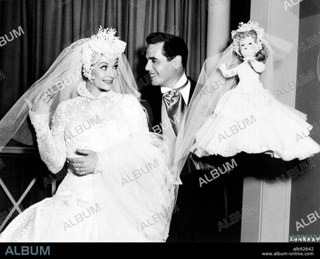 DESI ARNAZ et LUCILLE BALL dans FOREVER, DARLING, 1956, réalisé par ALEXANDER HALL. Copyright M.G.M. Lucille Ball, vestidad de novia para iniciar la película 'Forever, Darling', posa en compañía de Desi Arnaz y de la muñeca que le regalaron los empleados de guardarropía y departamento de maquillaje el primer día de filmación.