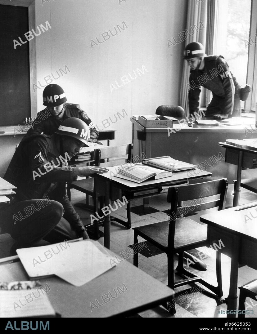 Three military policemen of the US Army, who are searching for bombs in front of the main entrance of the American school in Berlin on 24th September 1963, are checking a classroom. There was a bomb threat by phone before. 24/09/1963