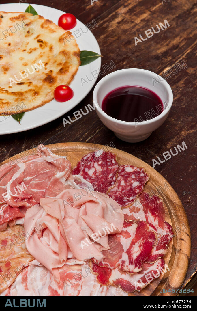 Osteria La Carrozza: tagliere di salumi tipici piacentini, piatto con una bortellina (una sorta di crepe senza uova) e vino rosso dei Colli piacentini.