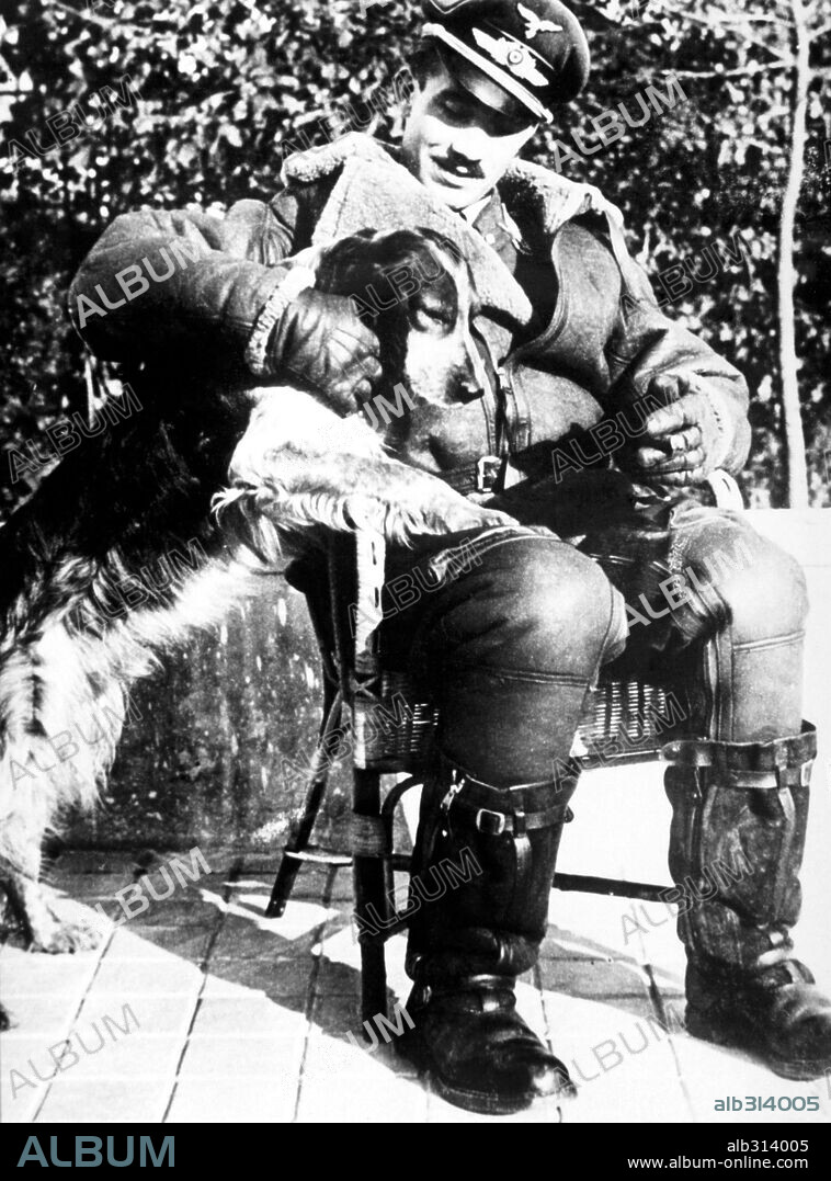 General Adolf Galland, a german ace pilot, on his uniform caressing a dog.