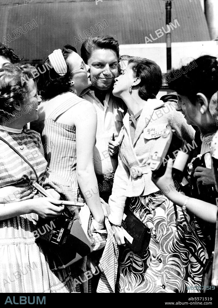 Feminine Hearts fluttered as American sing-ing star, Guy Mitchell greeted his fans at London Airport. He arrived by BOAC for a concert at the Palladium. August 16, 1955.