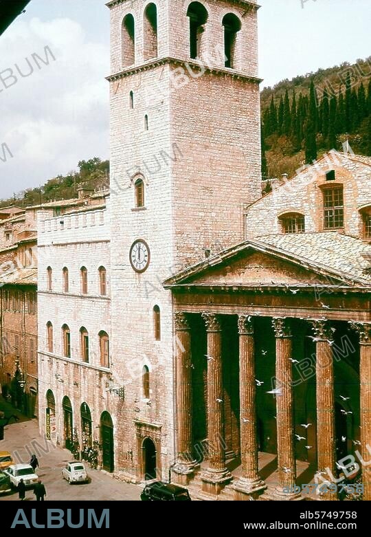 Assisi (Umbrien, Italien), Minervatempel. (1. Jahrhundert n. Chr.; 1539 Umbau zur Kirche S. Maria sopra Minerva). Piazza del Comune mit der Front des Minervatempels; links der Palazzo del Capitano del Popolo (13. Jh.) mit Torre del Popolo (erb. 1212-1305). Foto.