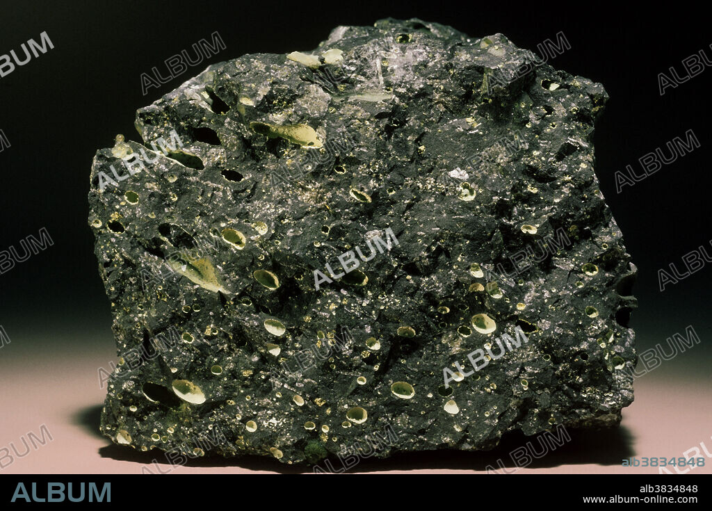 Basalt is a common and widespread dark colored igneous rock. It forms as a result of the cooling of lava flows or small intrusions; it is typically black and is composed primarily of plagioclase feldspar and pyroxene, and sometimes also olivine. The grain size is fairly small due to rapid cooling. Gas bubbles trapped in the cooling lava may be preserved as voids, known as vesicles, within the hardened rock. Sometimes fluids moving through the cooled rock deposit so-called secondary minerals, such as silica, calcite, chlorite and zeolites, within the vesicles. These mineral-filled cavities are known as amygdales (amygdules), and the rock is termed amygdaloidal.
