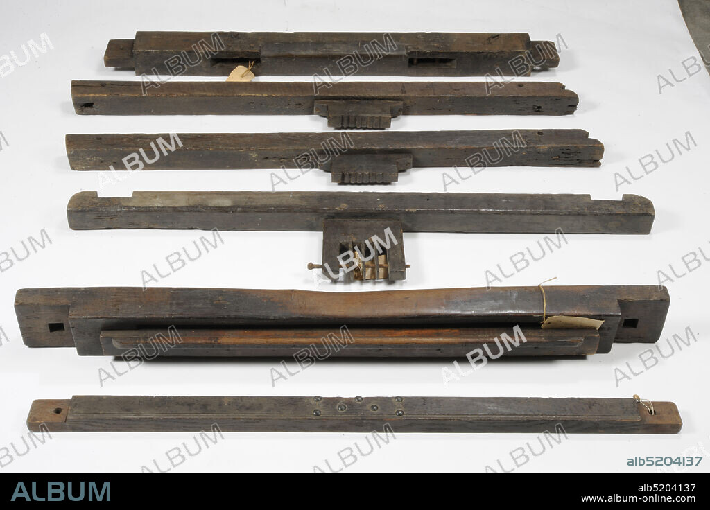 loom, Anonymous, early 20th century, wood, metal, textile, joinery, Largest part: 36 x 151 x 5cm (360 x 1510 x 50mm), Smallest part: 4.9 x 3.3cm (49 x 33mm), Loom of wood. Loom is in disassembled condition and consists of 140 parts. The parts consist of 43 wooden parts, including five slats with metal eyelets, two corner profiles, two wide planks with slots, a roll with brown bands, a roll with white cloth and various slats and beams. Furthermore, three metal bars, a metal reed and four wooden shafts with metal bars. In a carton box seventeen wooden parts, four with metal knurled washer, seventeen wooden plugs and shims and 55 metal parts, including two pulleys, seven wing nuts, a rod and screws, washers, bolts and a nut, 1997.