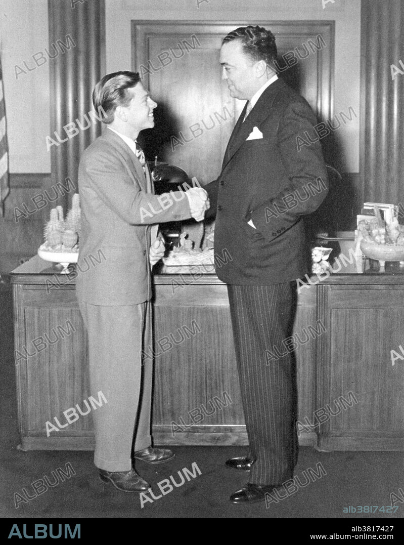 Director Hoover with actor Mickey Rooney in his office, 1940s. John Edgar Hoover (January 1, 1895 - May 2, 1972) was the first Director of the Federal Bureau of Investigation (FBI) of the United States. Appointed director of the Bureau of Investigation - predecessor to the FBI - in 1924, he was instrumental in founding the FBI in 1935, where he remained director until his death. Mickey Rooney (September 23, 1920 - April 6, 2014) was an American actor of film, television, Broadway, radio, and vaudeville. In a career spanning nine decades and continuing until shortly before his death, he appeared in more than 300 films and was one of the last surviving stars of the silent film era.