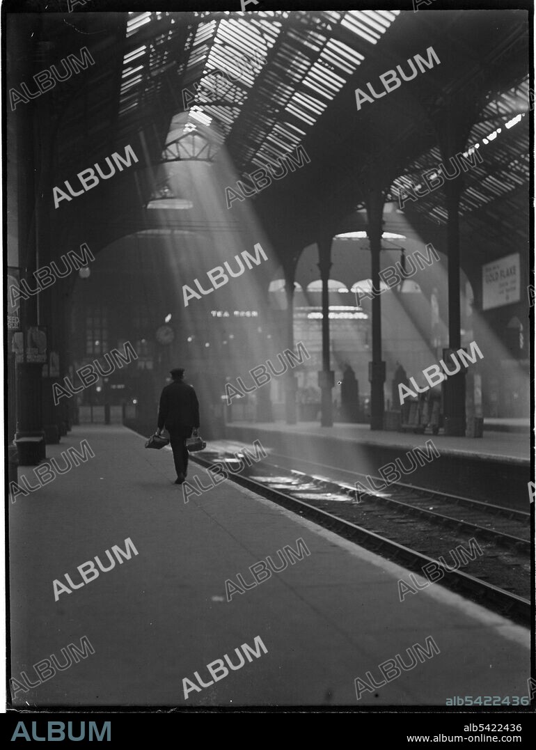 CHARLES WILLIAM PRICKETT. Liverpool Street Station, Liverpool Street, City of London, Greater London Authority, c1932. A view along a platform at Liverpool Street Station, showing beams of sunlight shining through the train shed roof on to the tracks.
