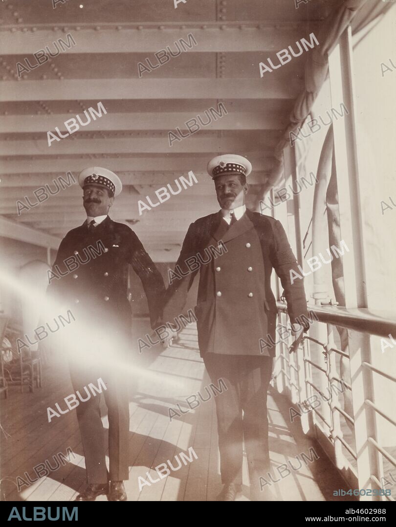 Two British naval officers hold hands and pull faces for the camera as they pose on the deck of the S.S. Balmoral Castle. Probably Atlantic Ocean, October 1910, 1910. 1995/076/1/4/1/3.