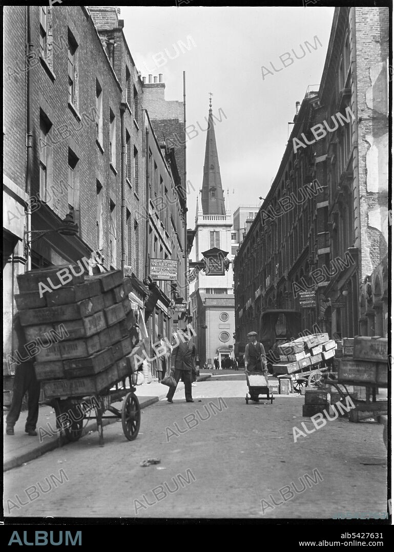 CHARLES WILLIAM PRICKETT. St Mary at Hill, City and County of the City of London, Greater London Authority, 1930s. A view looking north along St Mary at Hill towards St Margaret Pattens Church on Rood Lane, showing handcarts in the foreground loaded with crates. With its close proximity to the River Thames and the old Billingsgate Fish Market, the buildings on St Mary at Hill were occupied by a number of fish salesmen.