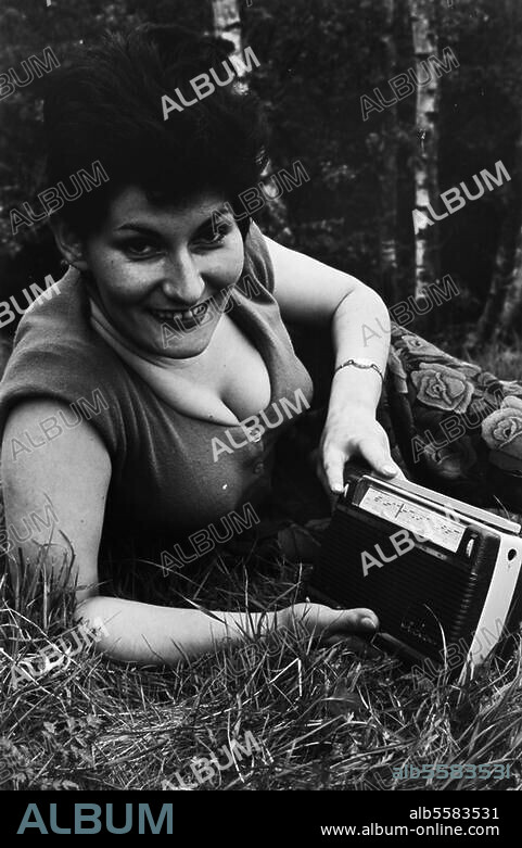 Technik:. Tontechnik / Rundfunk. Frau mit Kofferradio auf einer Wiese. (Werbeaufnahme für Kofferradios der Firma Blaupunkt). Foto, undat. (um 1960?).