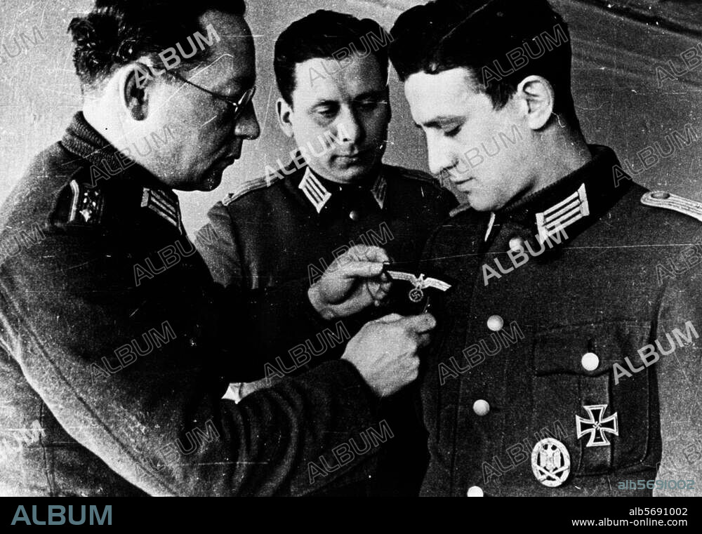 History / World War II / Nationalkomitee Freies Deutschland (Formed by German Communist emigrants & POWs in Moscow, 12-13/7/1943; campaigned via radio and leafleting for the overthrow of Hitler). - The secretary of a NKFD POW group removes the Nazi emblems from the uniform of lieutenant Philipps, who has joined the group. Photo, c. 1944.